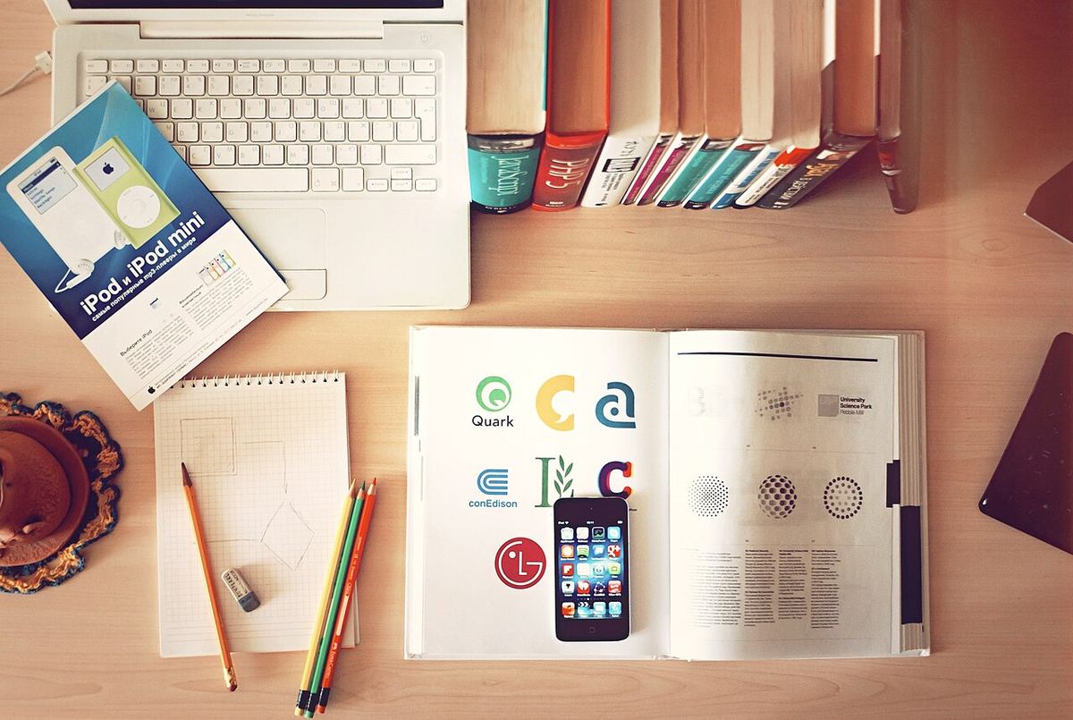 Bovenaanzicht van een bureau met laptop, boeken, potloden en een telefoon