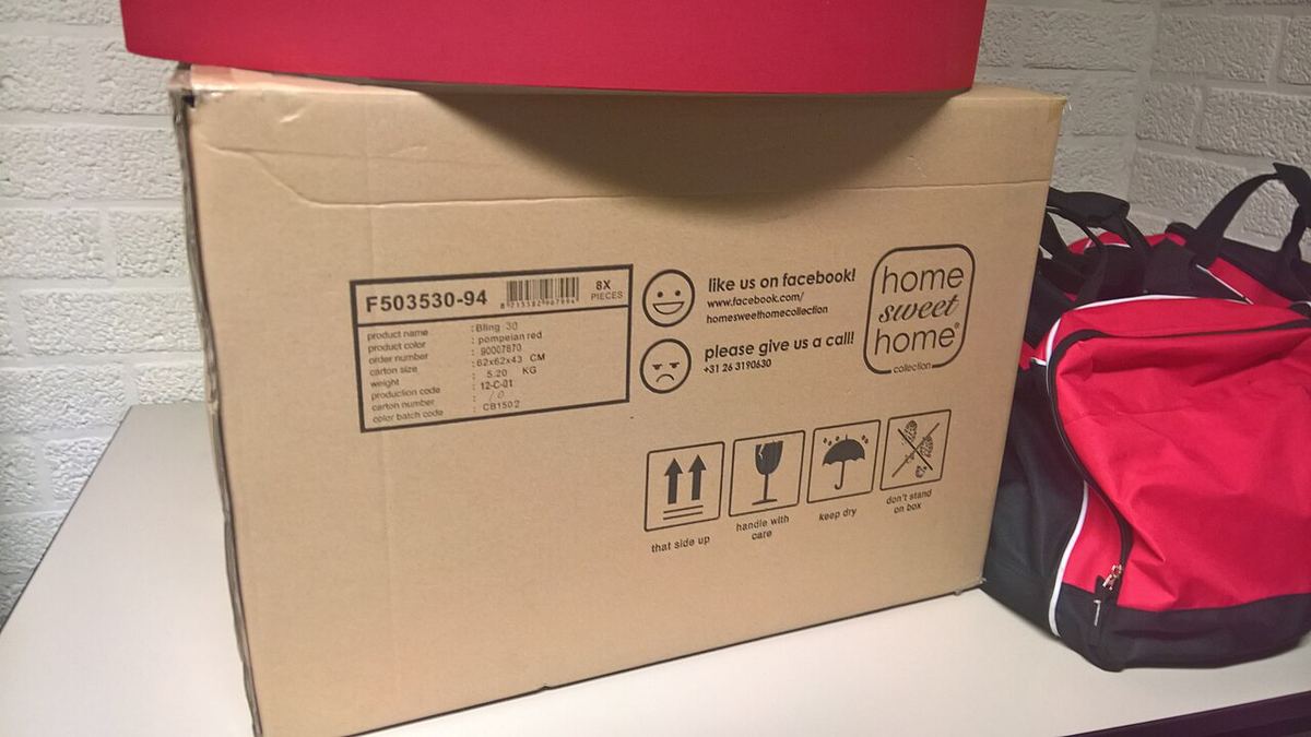 Kartonnen doos van een online bestelling naast een rode tas