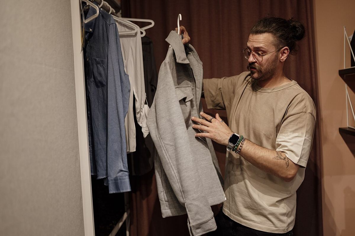 Man hangt kleding terug in een smalle kledingkast
