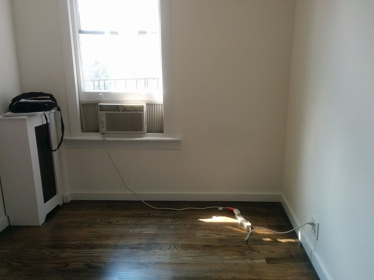 Lege kamer met een donkere houten vloer en een raam