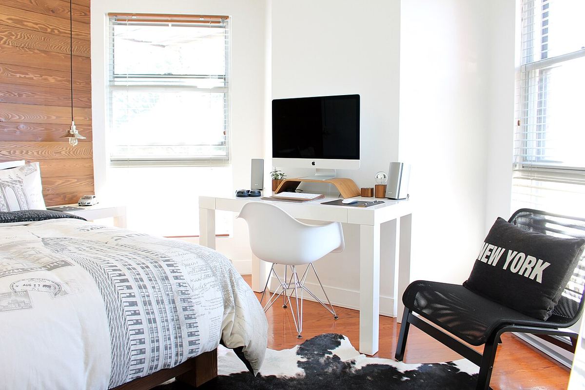 Loftslaapkamer met een wit bureau en een opgemaakt bed