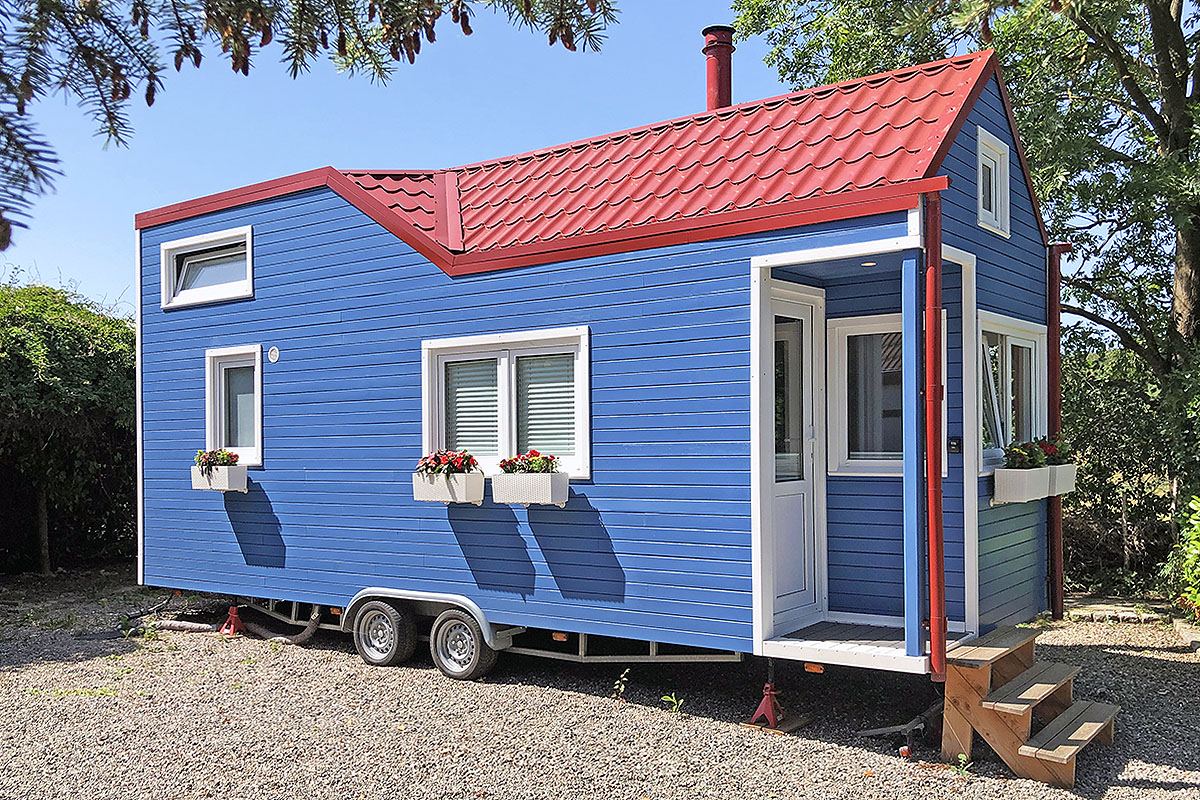 Blauw tiny house op een aanhanger met een rood dak