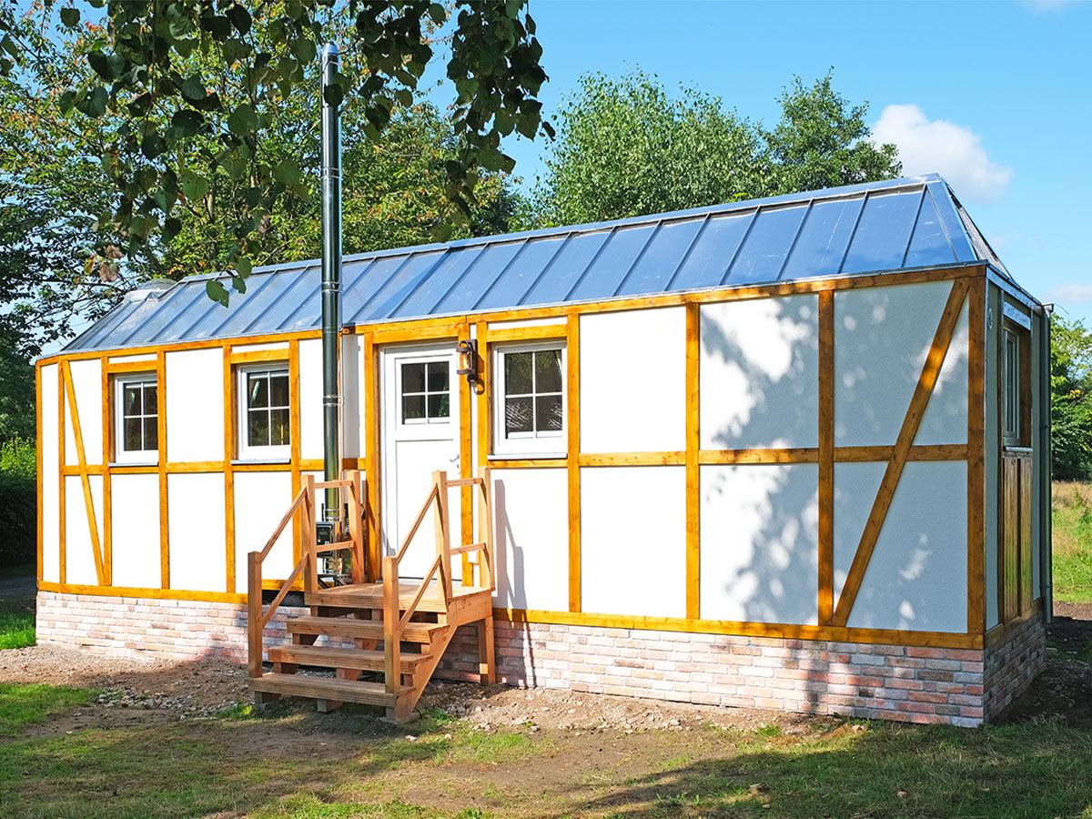 Wit tiny house met houten vakwerk en een klein trapje