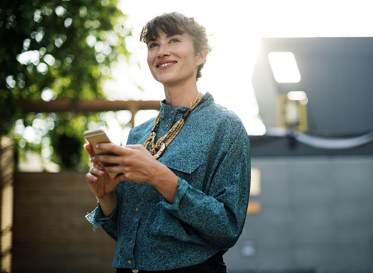 Vrouw kijkt glimlachend op van haar telefoon