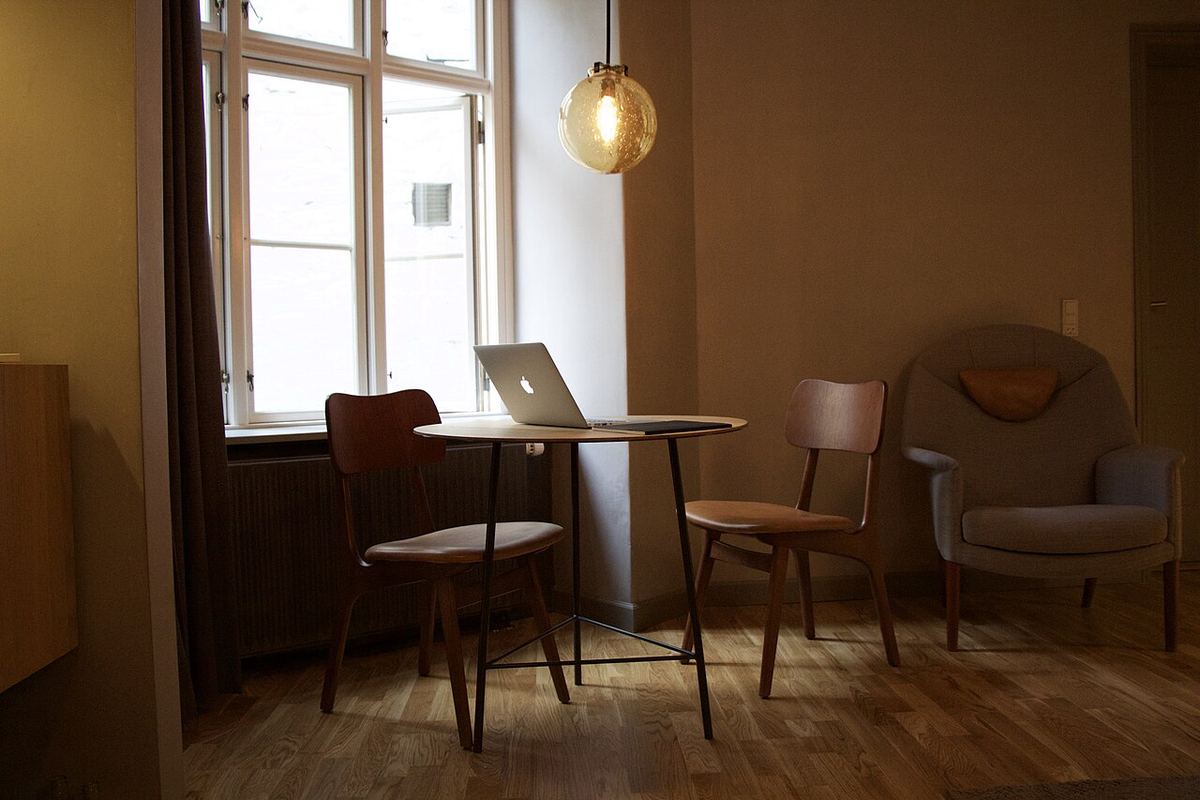 Opgeruimde eetkamer met een tafel, stoelen en een laptop